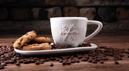 Coffee cup with chocolate cookies and coffee beans on wooden background
