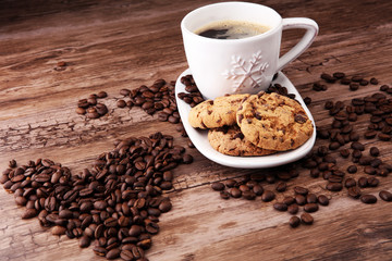 Coffee cup with chocolate cookies and coffee beans on wooden background