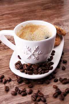 Coffee cup with chocolate cookies and coffee beans on wooden background