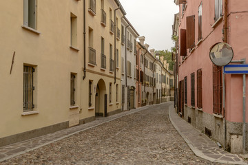 Fototapeta na wymiar old houses on bending cobbled street in city center, Mantua, Italy