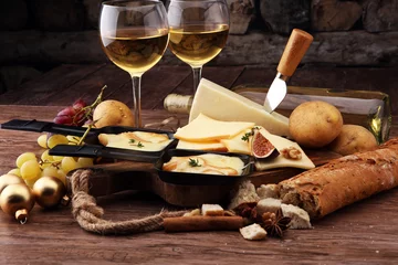  Delicious traditional Swiss melted raclette cheese on diced boiled or baked potato served in individual skillets © beats_