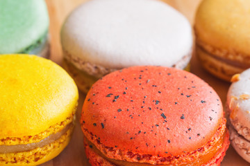 Close up colorful French or Italian sweet macaron on wood table in macro concept for background or wallpaper. Macarons is French dessert for afternoon tea or coffee break. Bakery frame concept.