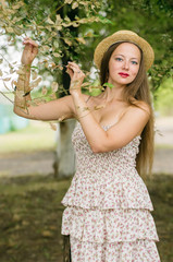 Girl in a straw hat and summer dress posing in a city park / Photographed in Russia, Orenburg
