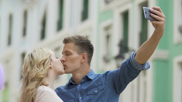 Beautiful couple taking selfie and kissing before camera, romantic date, love