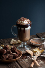 Coffee with cream and sloppy truffles on an old wooden table..