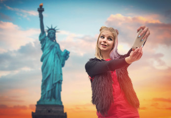 cheerful girl doing selfie on background Statue of Liberty