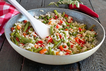 Rice cooked with vegetables and olive oil in a frying pan.