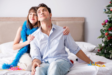 Young happy family celebrating christmas in bed