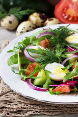 Fresh salad of quail eggs and vegetables on a white plate.