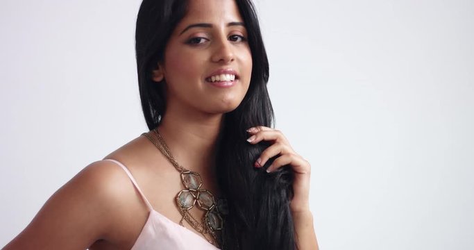 Portrait video of a smiling attractive exotic young woman with beautiful black straight hair wearing a large statement necklace