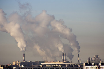 Smoke from pipes of plants against the background of the city