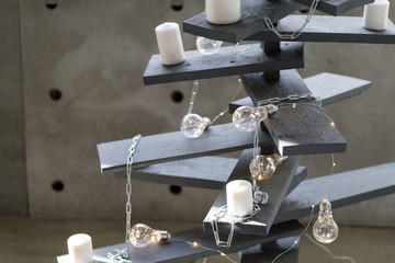Alternative wooden christmas tree. A handmade Christmas tree and light bulb on the floor in the room