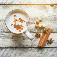 Hot cocoa drink in rustic mug. Cinnamon sticks and anise stars on wooden table. Christmas cozy scene. Top view.