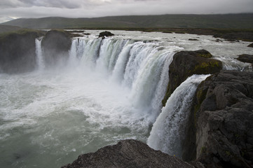 Wonderful view of Gadafoss Falls in a typical Icelandic landscape, a wild nature of rocks and shrubs, rivers and lakes.