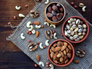 Fototapeta na wymiar different varieties of nuts on a wooden background - almonds, cashews, walnuts, hazelnuts, pistachios