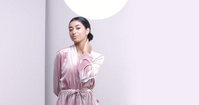 Beautiful Middle Eastern girl adjusting the bow on her luxurious spa silk dressing gown on white background
