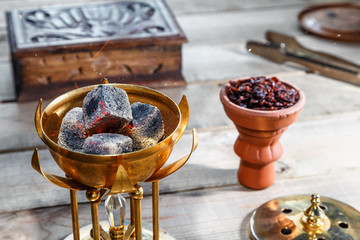 burning coals for Shisha Smoking are in the Golden bowl, made in the shape of a Lotus on the background of Smoking accessories