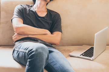Naklejka premium Close up of young man sleeping on the sofa at home with laptop.