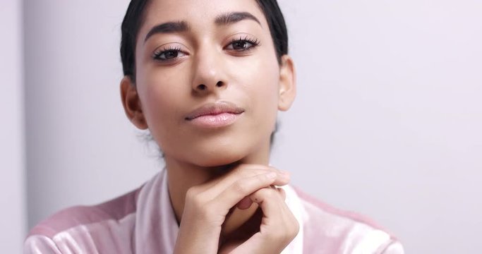 Close up video of a beautiful young female model with flawless light brown skin in a pink dressing gown