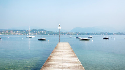 Fototapeta na wymiar Wooden Pier in the middle of the Beautiful Garda Lake Scenery, Italy.