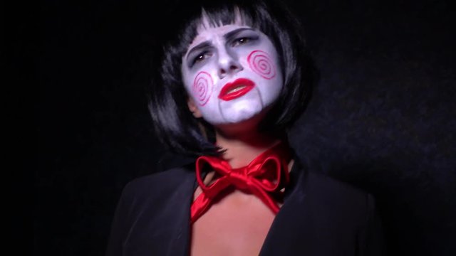 Girl with make-up in nightmare style sings on a black background