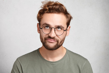 Portrait of stylish bearded man with bored fed up expression, looks displeased up, being tired to...