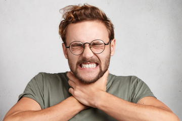 Obraz premium Distress and depression concept. Grieved frustrated male makes suicide gesture, clenches teeth and closes eyes, regret something, has stressful expression. Negative emotions and feelings concept