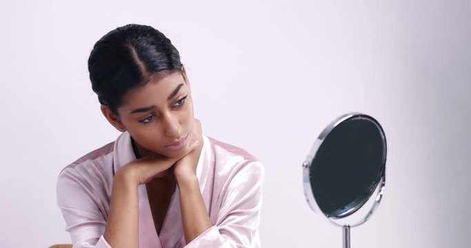 Beautiful Moroccan young woman in dressing gown sitting at a table with a round mirror getting ready for her skincare routine
