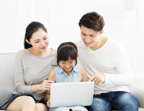 Happy Asian Family With Laptop On Sofa