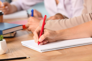 Female student writing in copybook at table