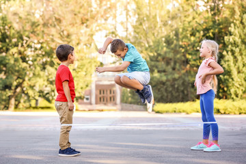 Adorable children playing elastic game outdoors