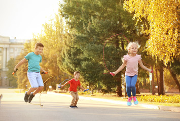 Adorable children skipping rope outdoors