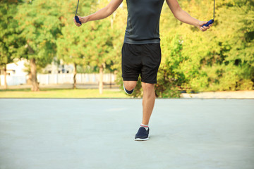 Young sporty man jumping rope outdoors