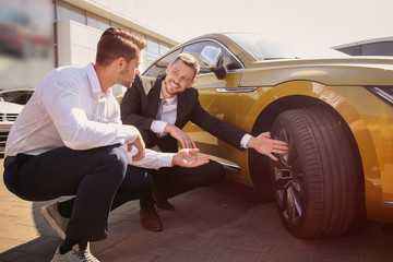 Salesman showing new car to customer outdoors