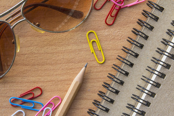 Office supplies on the table. Notebooks, paper clips, pencils and glasses.