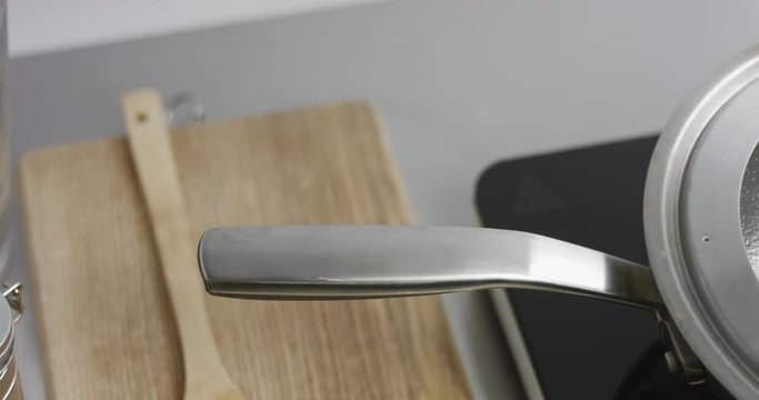 Panning video of water boiling in a large stainless steel pot in a minimalist kitchen