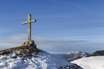 wooden cross on top of a mountain covered with snow.