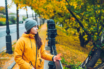 Naklejka premium Woman walking on a street full of yellow leaves during Autumn