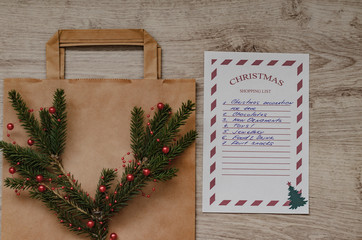 Christmas shopping list with spruce branch and eco shopping bag.