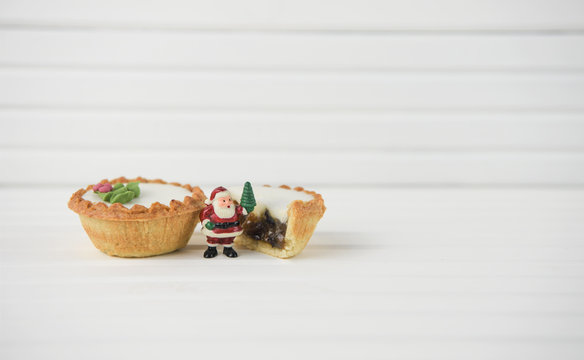 christmas photography food image of mince pie and eaten pie with miniture santa claus father christmas with xmas tree on white background