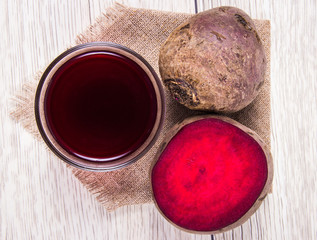 Healthy beetroot juice and fresh vegetables on wooden background.