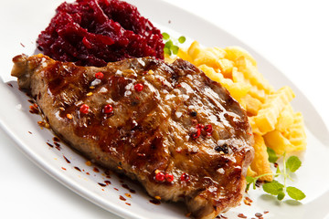 Grilled steak, French fries and vegetables on white background