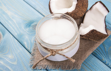Coconut oil and fresh coconuts on a wooden table.