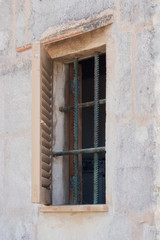 Window with grating in old stone house in Spain
