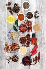 Hot herb and spice seasoning with chili pepper selection, mustard powder and seeds, ground and whole peppercorns, chilli and olive oil on rustic wood background. Top view.