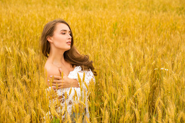 Fototapeta na wymiar Portrait of a young girl on a background of golden wheat field