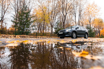 Black SUV on autumn road in rainy day