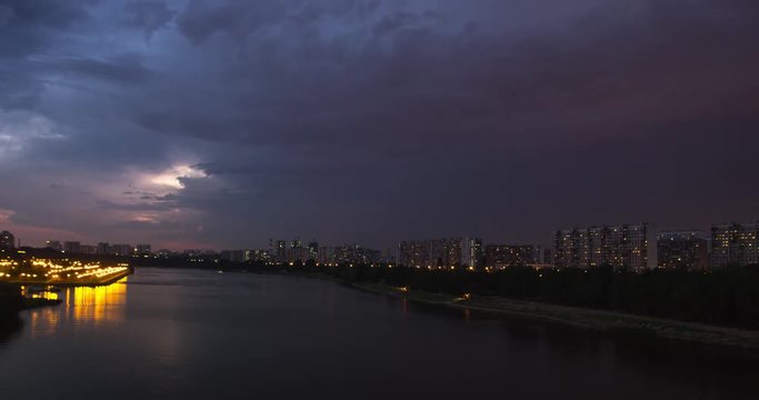 Time lapse cityscape of tour boat traffic on river and the movement of the thunderstorm front at dusk. Apartments buildings at background.