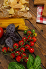 Pasta background. Dry spaghetti with vegetables and herbs on a wooden table.