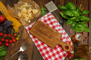 Pasta background. Dry spaghetti with vegetables and herbs on a wooden table.